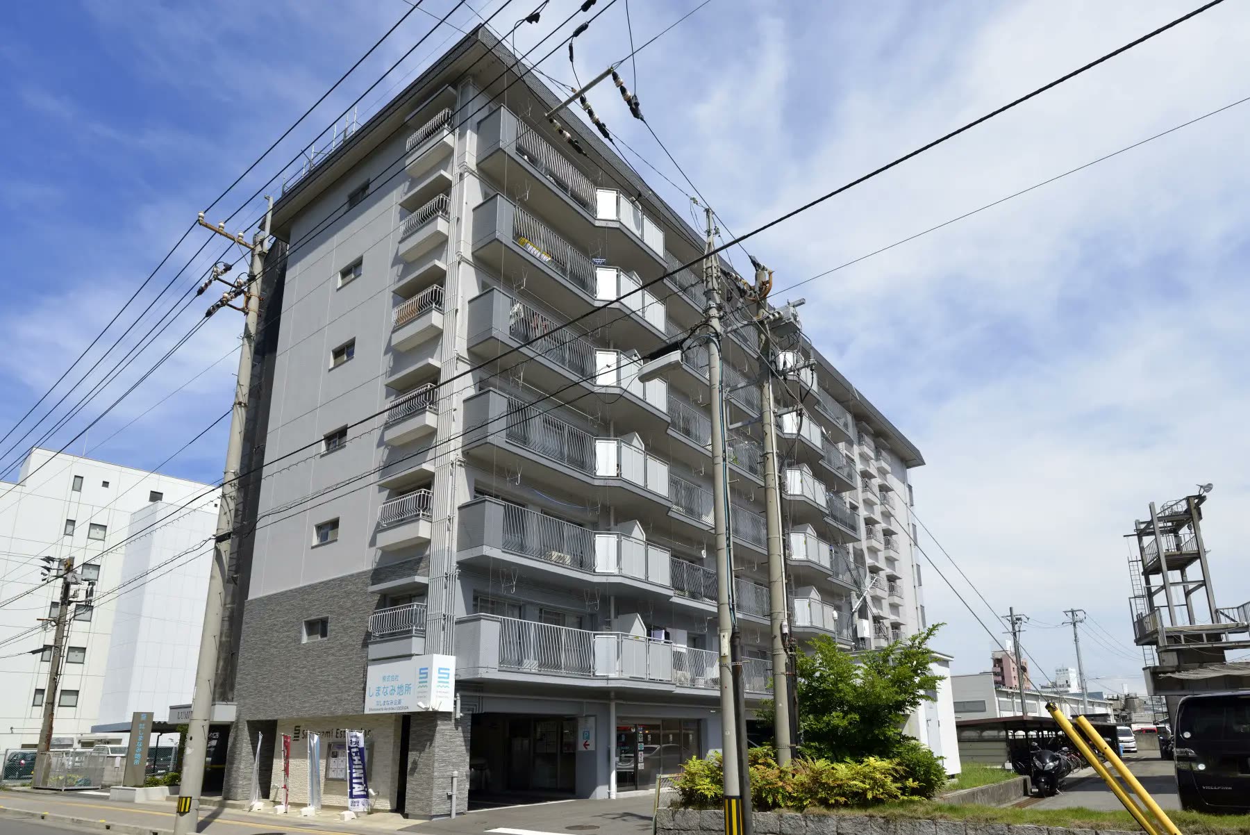 青空の下に建つ、白とグレーの8階建ての賃貸マンション「ルミウス」