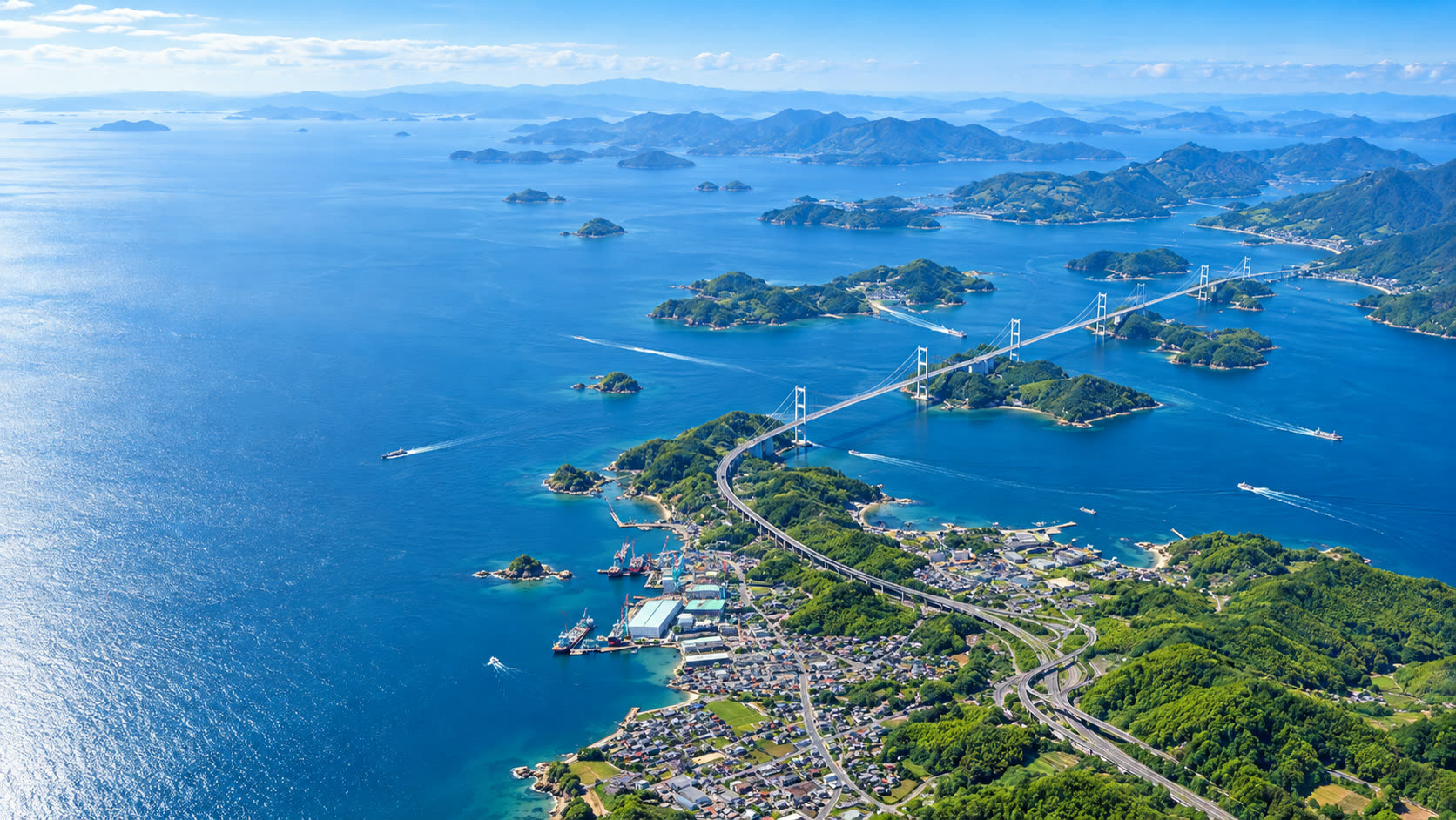 上空から見た、しまなみ海道と来島海峡大橋。青い瀬戸内海に緑の島々が浮かぶ